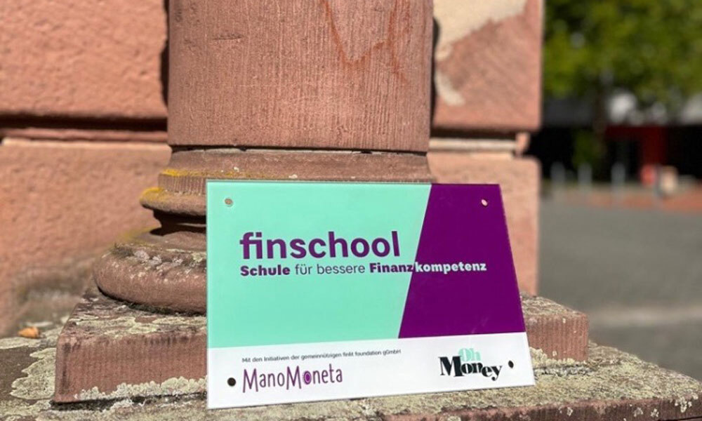Schulschild finschool vor einer Mauer